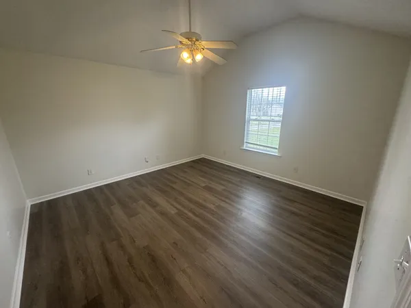an empty room with wooden floor and chandelier fan