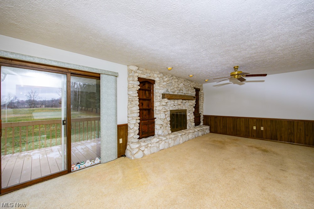 4251 Seville Road Seville, OH 44273 - Photo 9 of 20 Unfurnished living room featuring carpet flooring, a fireplace, a textured ceiling, and ceiling fan