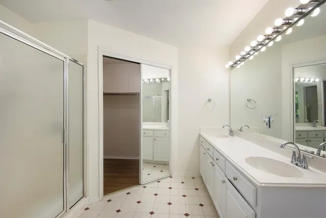 a spacious bathroom with a sink a toilet a shower and a mirror