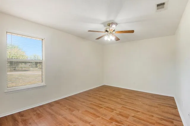 an empty room with a window and a fan