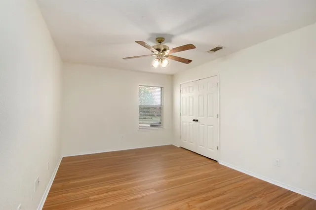 a view of a room with wooden floor and a ceiling fan