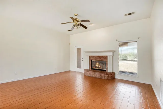 wooden floor fireplace and windows in an empty room