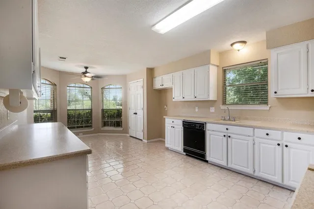a large kitchen with cabinets a sink a window and stainless steel appliances