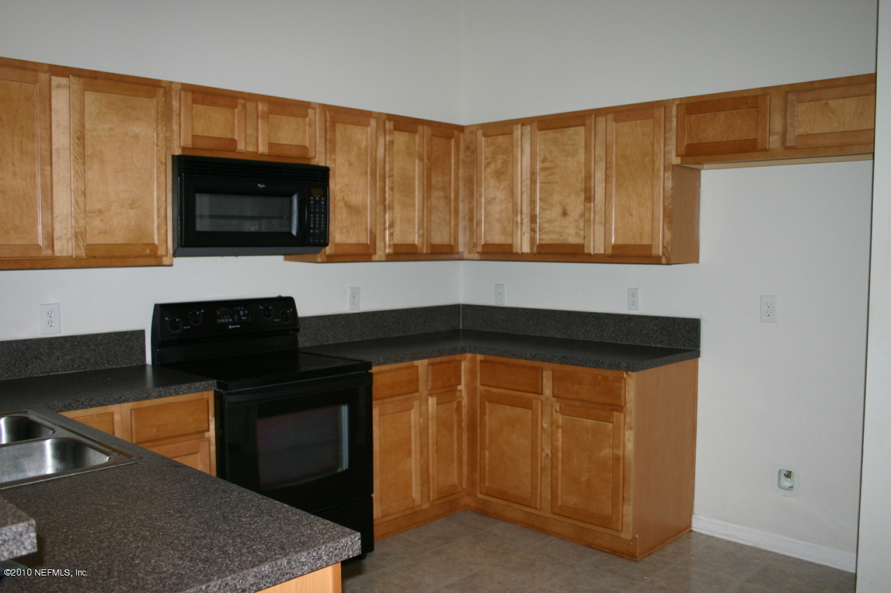 7920 Merrill Road, Unit 1002 Jacksonville, FL 32277 - Photo 5 of 18 a kitchen with stainless steel appliances wooden cabinets and a stove top oven
