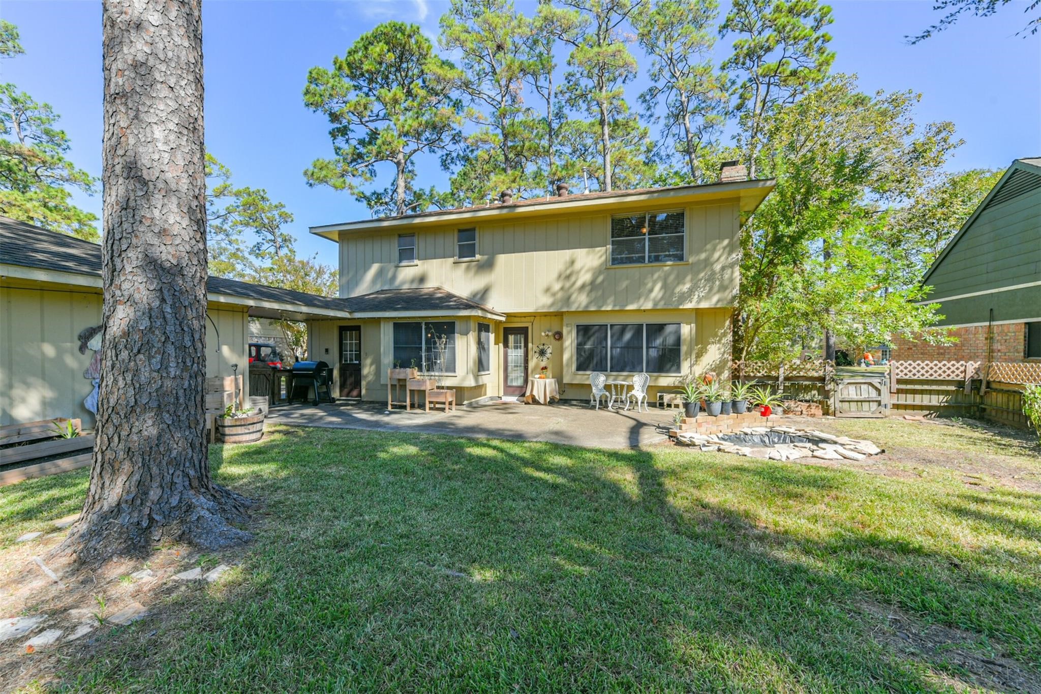 3728 Autumn Lane Baytown, TX 77521 - Photo 15 of 16 This photo showcases the backyard of a two-story house, featuring a spacious lawn, mature trees, a cozy patio area, and a small garden.