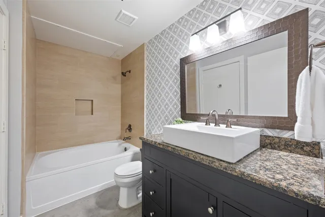 a bathroom with a granite countertop sink toilet mirror and bathtub