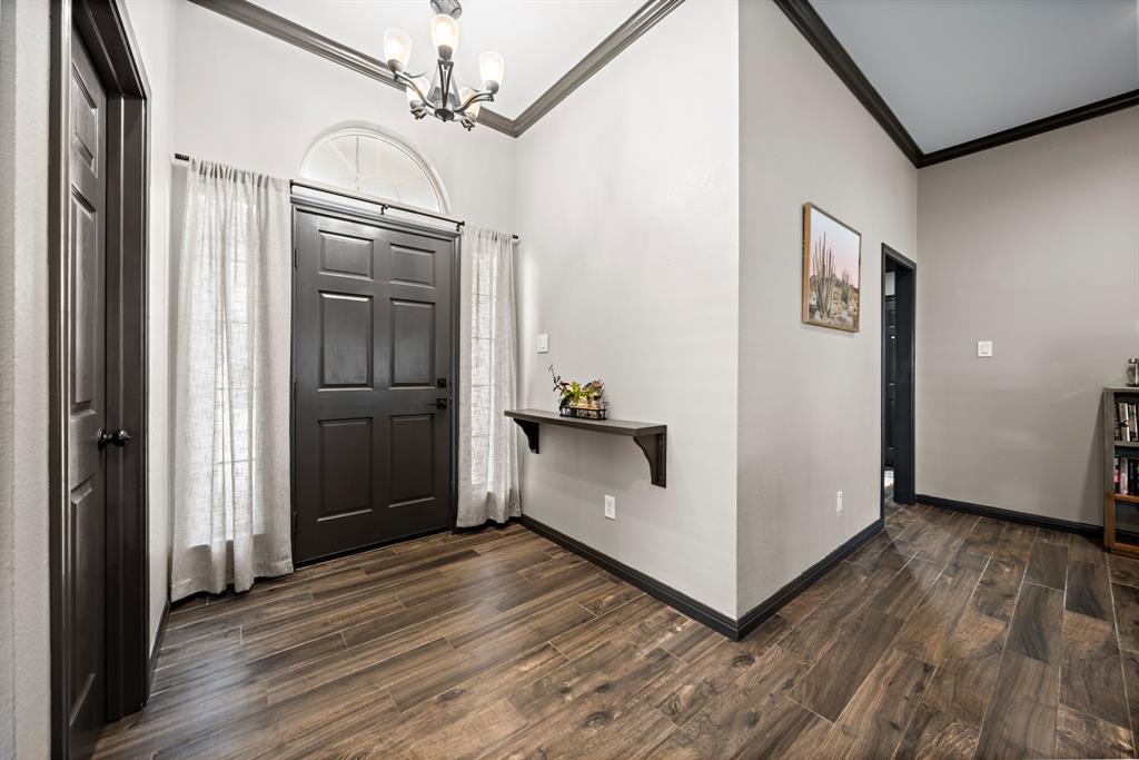 10512 Whitney Trace Drive Waco, TX 76708 - Photo 24 of 39 Entryway featuring a dark paneled door with an arched transom window, wood-finish flooring, and a built-in floating shelf