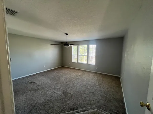 an empty room with a window and a ceiling fan view