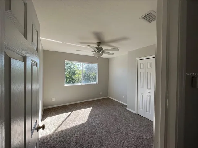 an empty room with a ceiling fan and a window