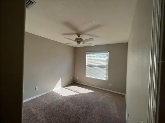 an empty room with a ceiling fan and a window