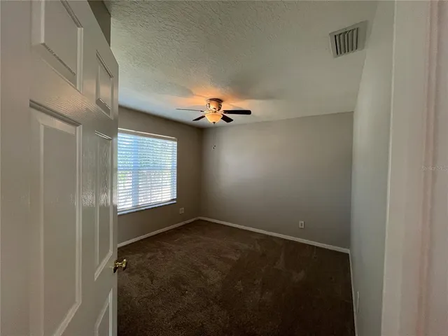 an empty room with closet and a ceiling fan