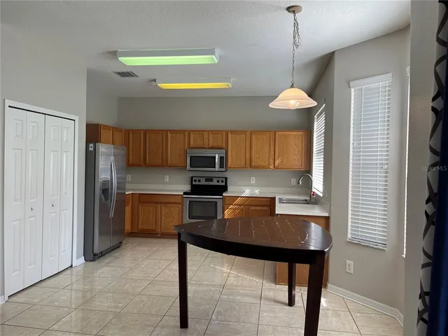 a kitchen with stainless steel appliances granite countertop a sink a stove a refrigerator a microwave oven a dining table and chairs with wooden floor