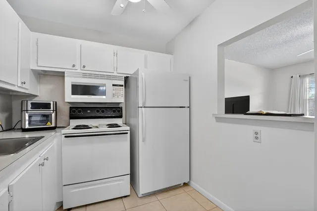 a kitchen with stainless steel appliances granite countertop a refrigerator sink and white cabinets