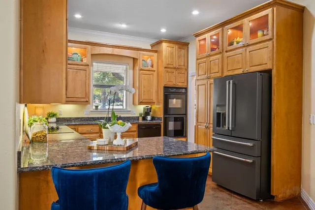 a kitchen with stainless steel appliances granite countertop a refrigerator a sink and a stove