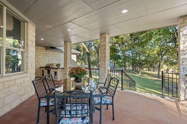 a view of a patio with table and chairs and floor to ceiling window next to a yard