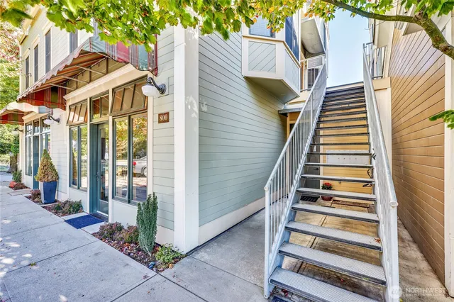a view of a white house next to a yard with plants and trees
