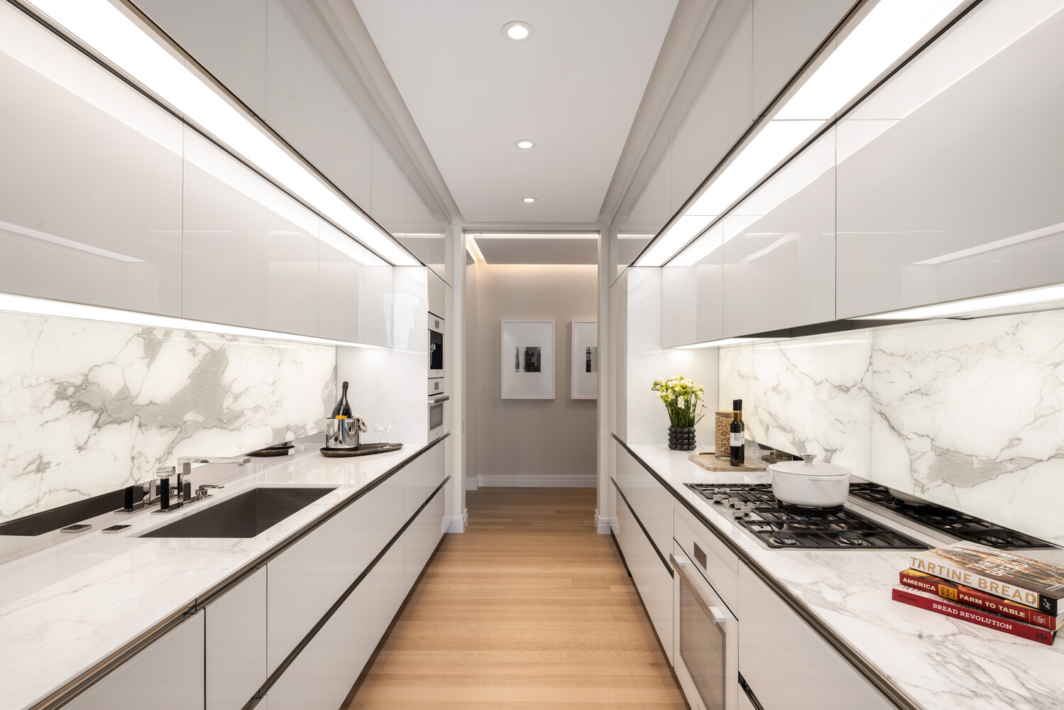 53 West 53rd Street, Unit 20D Manhattan, NY 10019 - Photo 4 of 12 a large white kitchen with stainless steel appliances a stove a sink and a refrigerator
