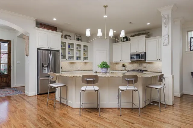 a large kitchen with stainless steel appliances granite countertop a stove a sink dishwasher and a refrigerator with wooden floor