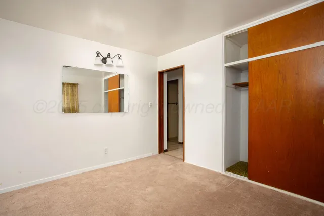 an empty room with wooden floor closet and windows