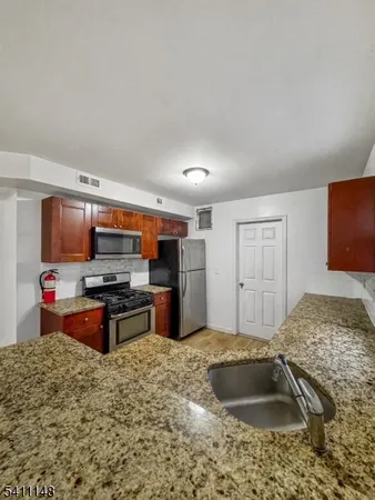 a kitchen with stainless steel appliances granite countertop a sink stove and refrigerator
