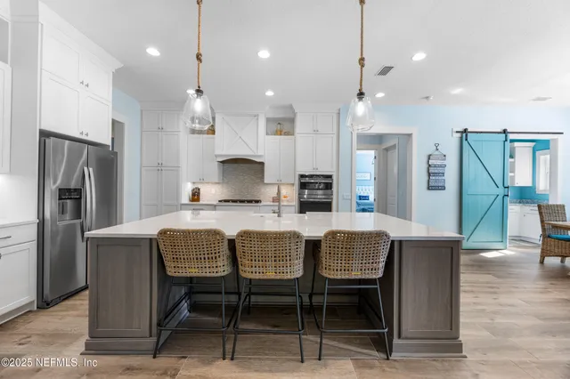 a kitchen with kitchen island a stove a sink a refrigerator a dining table and chairs