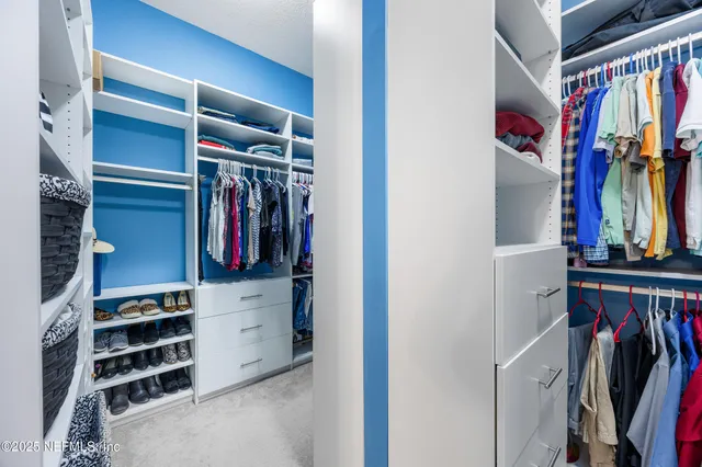 a view of walk in closet with clothes and shoes
