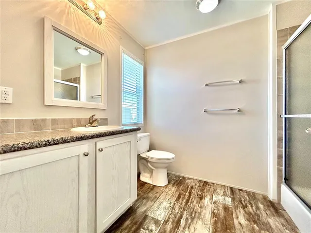 a bathroom with a granite countertop sink toilet and shower
