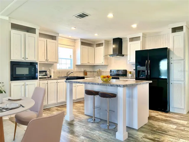 a kitchen with stainless steel appliances granite countertop a stove a sink dishwasher a refrigerator and a microwave