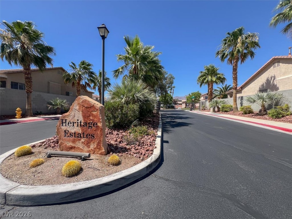 7308 Rustic Meadow Street Las Vegas, NV 89131 - Photo 27 of 27 Enter a serene community through the Heritage Estates monument, featuring lush palm landscaping under a vast blue sky.