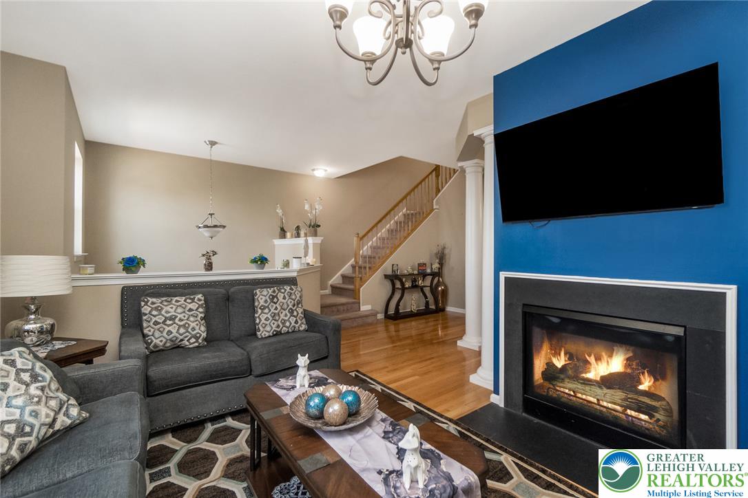 3566 Penfield Way Nazareth, PA 18064 - Photo 22 of 47 A welcoming living room featuring a warm fireplace and rich hardwood flooring, perfect for cozy gatherings.