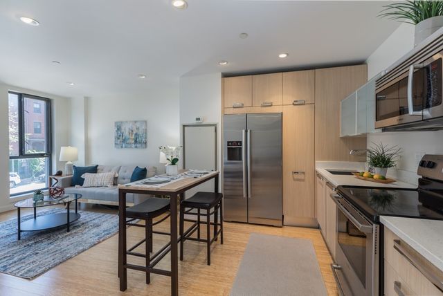a kitchen with stainless steel appliances a table chairs refrigerator and a microwave