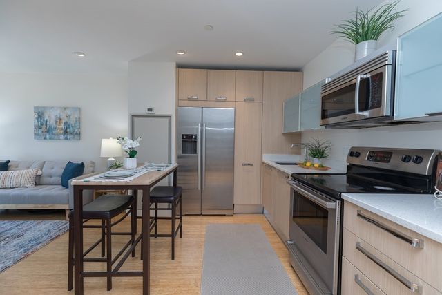 a kitchen with stainless steel appliances a stove a refrigerator and a dining table