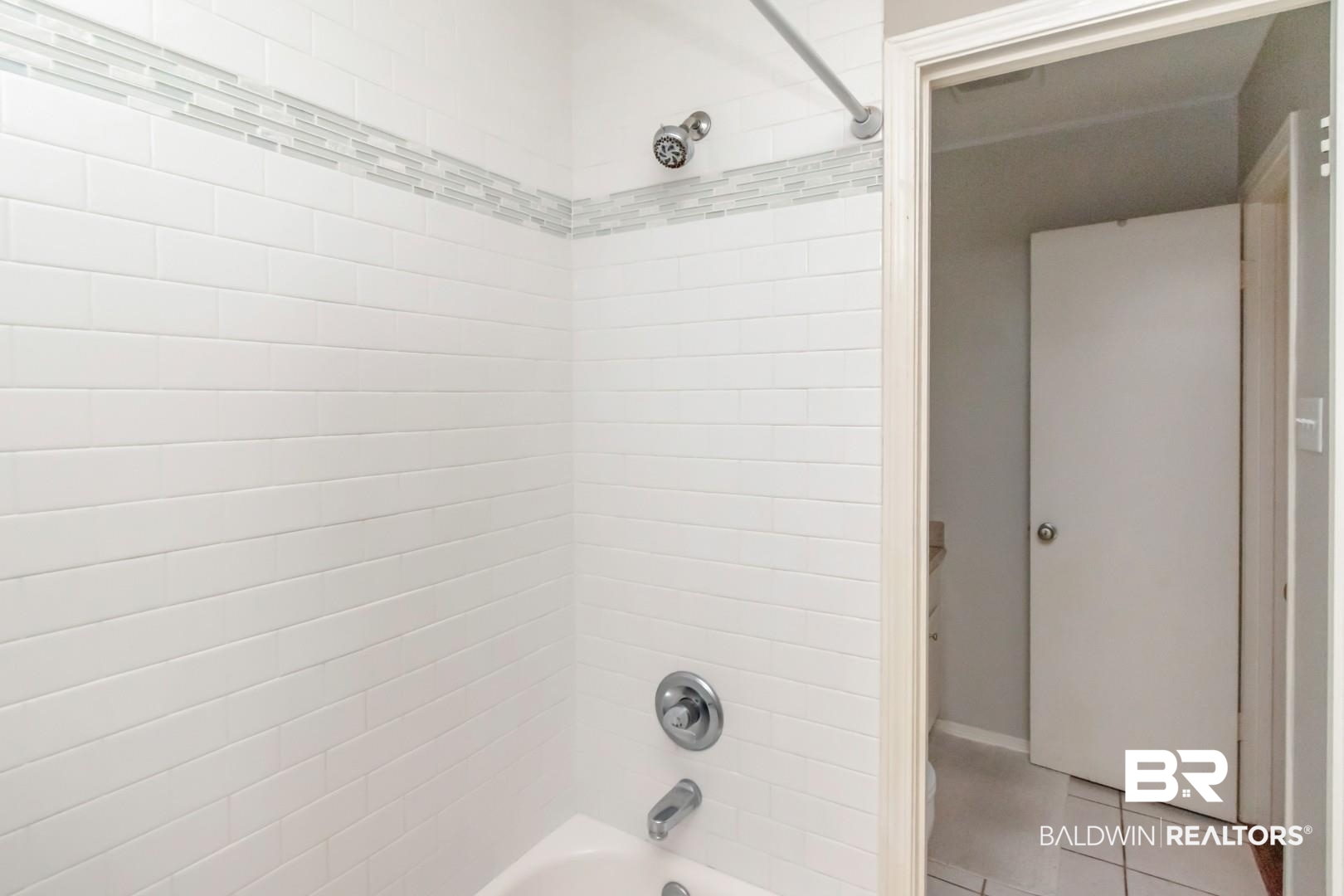 118 Du Rhu Drive, Unit H Mobile, AL 36608 - Photo 17 of 19 White subway tile shower surround with a decorative mosaic accent band, chrome showerhead, and tub faucet
