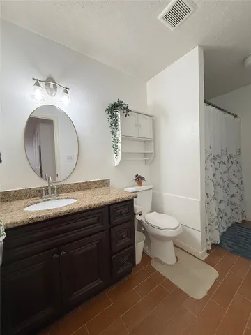 a bathroom with a granite countertop toilet a sink and a mirror