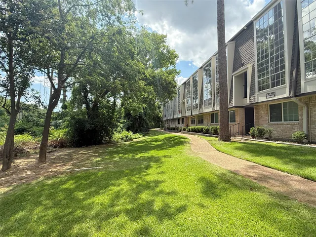 a view of a house with a big yard and large trees