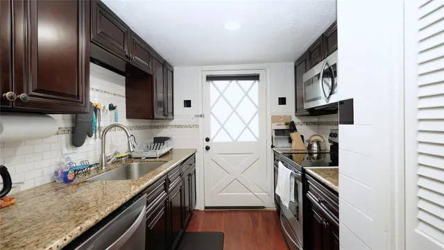 a kitchen with granite countertop a sink stainless steel appliances and cabinets