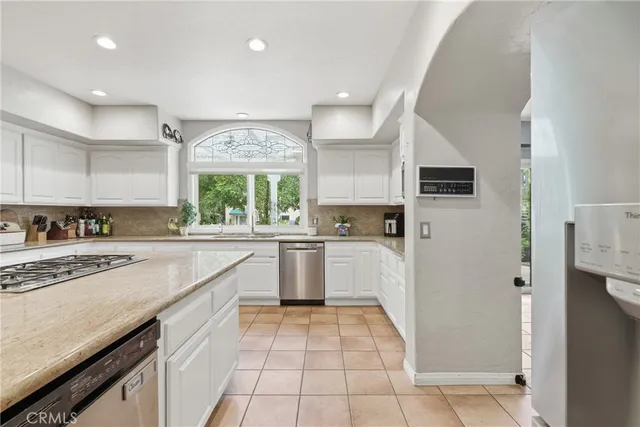 a kitchen with white cabinets appliances and a window