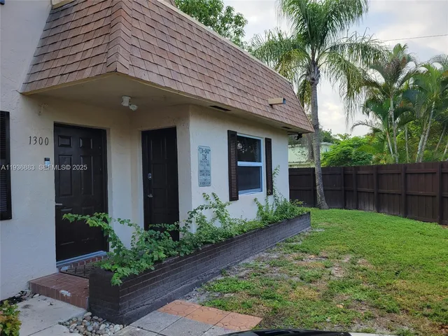 a view of a house with a small yard plants and palm trees