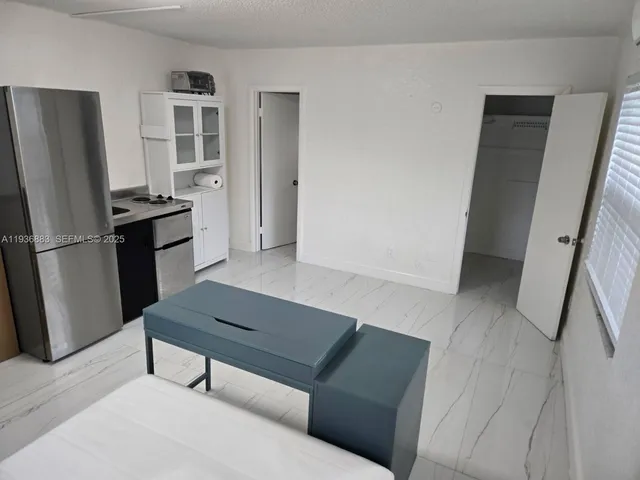 a living room with a bed furniture and a refrigerator