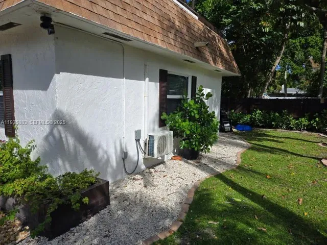 a view of a white house with a yard plants and a lawn chair