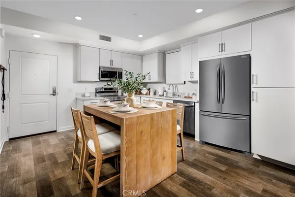 a kitchen with a refrigerator a sink and a stove top oven with wooden floor