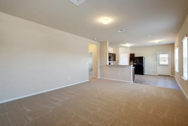 a view of an empty room with a window and a kitchen