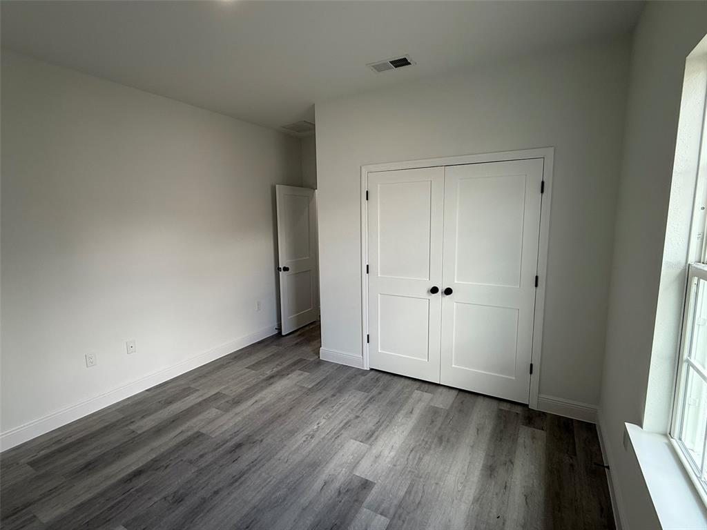 4875 Southwest 159th Lane Ocala, FL 34473 - Photo 22 of 32 a view of an empty room with wooden floor and a window