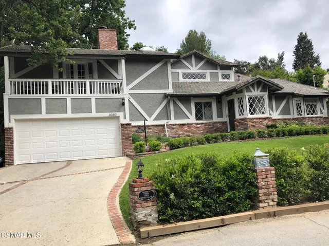 a front view of a house with a yard and potted plants