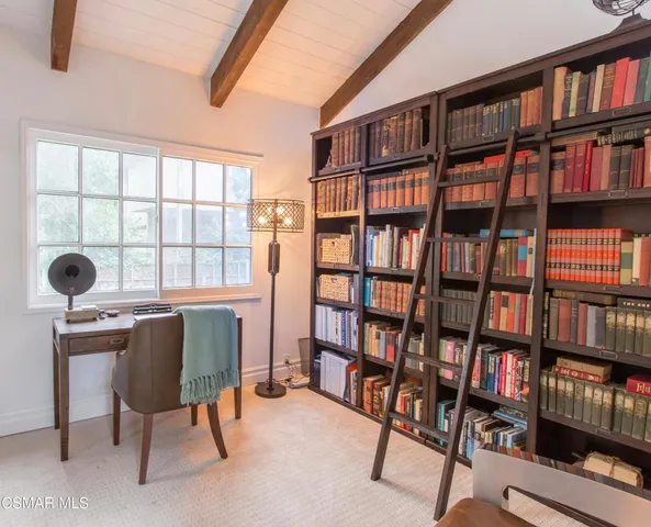 a view of a workspace with bookshelf and a window