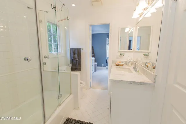 a bathroom with a granite countertop sink a mirror and shower
