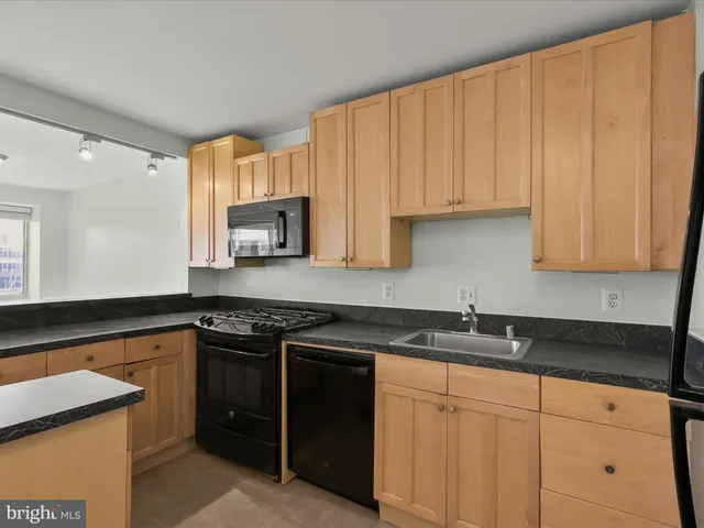 a view of an empty room with kitchen and a window