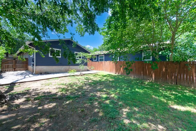 a backyard of a house with table and chairs under an umbrella