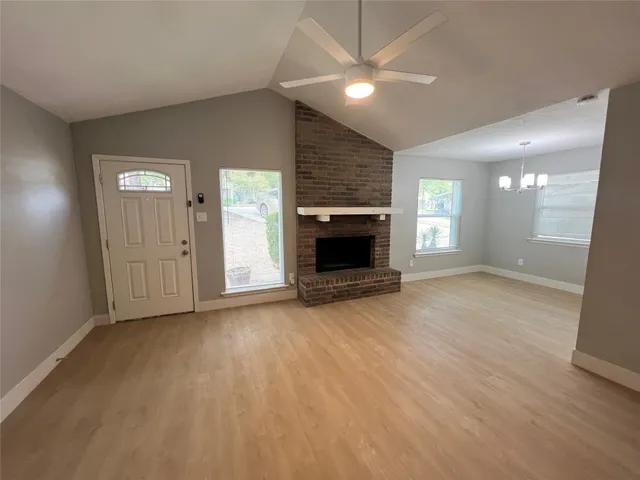 an empty room with wooden floor fireplace and windows