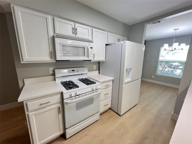 a kitchen with white cabinets white stainless steel appliances and sink